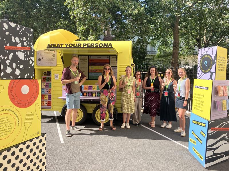 Researchers standing in front of a yellow horsebox that says Meat Your Persona